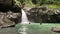 Romantic couple holding hands and jumps into the waterfall on summer day.