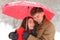 Romantic couple hugging under umbrella snowing in winter