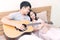 Romantic couple in love young man playing guitar for his girlfriend in the bedroom. Handsome man play music with acoustic