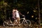 Romantic couple, man and attractive girl close together at tandem bicycle in dark autumn park.