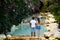 Romantic couple. Multiethnic couple at the swimming pool. View from back. Swimming pool surrounded by pink bougainvillea flowers