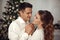 Romantic couple portrait in love. Cheerful Happy newlywed hugging by xmas tree in Christmas interior on winter holidays.