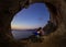 Romantic couple of rock climbers watching sunset from cave in cl