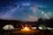 Romantic couple sitting at campfire near tents in the night