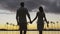 Romantic couple at sunset holding hands at beach walking hand in hand vacation