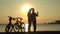 Romantic couple at sunset. Silhouette of bicycles on sunset.