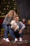 Romantic couple with their dog make fun near Christmas tree in festive aesthetic cozy home interior. Good mood of