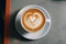 Romantic cup of latte coffee with heart shaped art on foam, top view on love background
