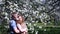 Romantic dreamed couple in blossoming cherry orchard with lots of flowers. Happy young man embraces his girlfriend with