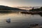 Romantic dusk scene of beautiful mute swan and moored boats in Lake Windermere