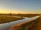 Romantic Dutch countryside amidst extensive grassy meadows and canals whose water reflects the sunset