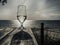 Romantic evening sunset with misty glass of white wine on background sea, on wooden table