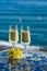 Romantic event, bottle with cold sparkling wine, cava or champagne served with two glasses on table with sea view and palm tree