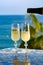 Romantic event, waiter pouring cold sparkling wine, cava or champagne served with two glasses on table with sea view and palm tree