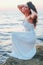 Romantic feminine woman in white dress waiting at the shore