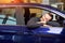 Romantic funny smiling man leaning on the door, window of a new blue luxury car