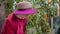 Romantic girl in hat spraying plants in indoor garden orangery. Young smiling floristspraying ficus tree for care in