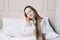 Romantic girl. Portrait of a girl in bed with natural flowers. Dreamy young woman with pink tulips resting in bedroom in morning