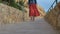 Romantic girl in red skirt walk down the road at the coast side