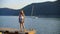 Romantic girl standing on sea pier on white yacht and green highlands landscape. Cute teen girl posing on lake pier on