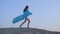 Romantic girl teenager in blue tunic waving on wind walking on sandy dune on sunset sky landscape. Barefoot girl in blue