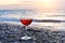 Romantic glass of wine sitting on the beach at colorful sunset, Glass of red wine against sunset, red wine on the sea ocean