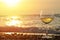 Romantic glass of wine sitting on the beach at colorful sunset Glasses of white wine against sunset, white wine on the sky backgro