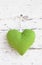 Romantic green dotted heart shape hanging above white wooden surface on a nail- white wooden shabby chic background for