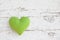 Romantic green dotted heart shape hanging above white wooden surface on a nail- white wooden shabby chic background for