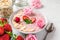 Romantic healthy breakfast. overnight strawberry oats with fresh berries, almonds and mint in a bowl with rose flowers