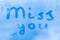 The romantic inscription miss you on the blue evening or morning window glass