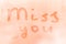 The romantic inscription miss you on the orange or pink evening or morning window glass