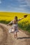 Romantic latino woman barefoot on a road in canola field