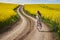 Romantic latino woman barefoot on a road in canola field