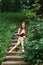 A romantic long-haired young woman with bare feet sits on a staircase in the open air and reads a book