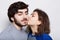 Romantic loving couple. A pretty brunette kissing his bearded boyfriend in his chin. A happy couple closing their eyes from pleasu