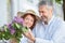 Romantic mature couple walking through town, man giving bouquet of lilac flowers to his wife