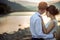 Romantic outdoor portrait of the charming just married tenderly hugging and enjoying the sunset on the river bank.