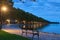 Romantic and peaceful scene. Empty bench illuminated by lamppost. Morning landscape view of Lake Balaton and Plane tree alley