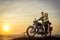 Romantic picture with a couple of beautiful stylish bikers at sunset. Handsome guy with tatoo and young sexy woman enjoy