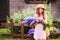 Romantic portrait of happy child girl picking bouquet of beautiful blue delphinium flowers