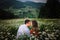Romantic portrait of the joyful smiling couple tenderly rubbing noses while sitting on the blooming daisy meadow at the
