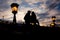 Romantic portrait of the loving couple silhouette sitting on the Chain Bridge near the lightning street lamp in Budapest