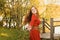 Romantic portrait of the woman in airy red dress dancing on the bridge