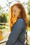 Romantic redhead young woman in denim shirt posing in rays of s