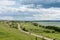 Romantic road into the distance, horizon, lake and green flat plain.