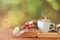 romantic scene of cup of coffee next to old book in front of countryside bokeh landscape background.