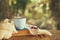 romantic scene of cup of coffee next to old book in front of countryside bokeh landscape background.