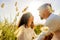 Romantic scene of multiracial passionate young couple in love looking in eyes each other among high grass vegetation at sunset or