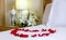 Romantic setup with honeymoon bed with focus on the heart-shaped rose petals